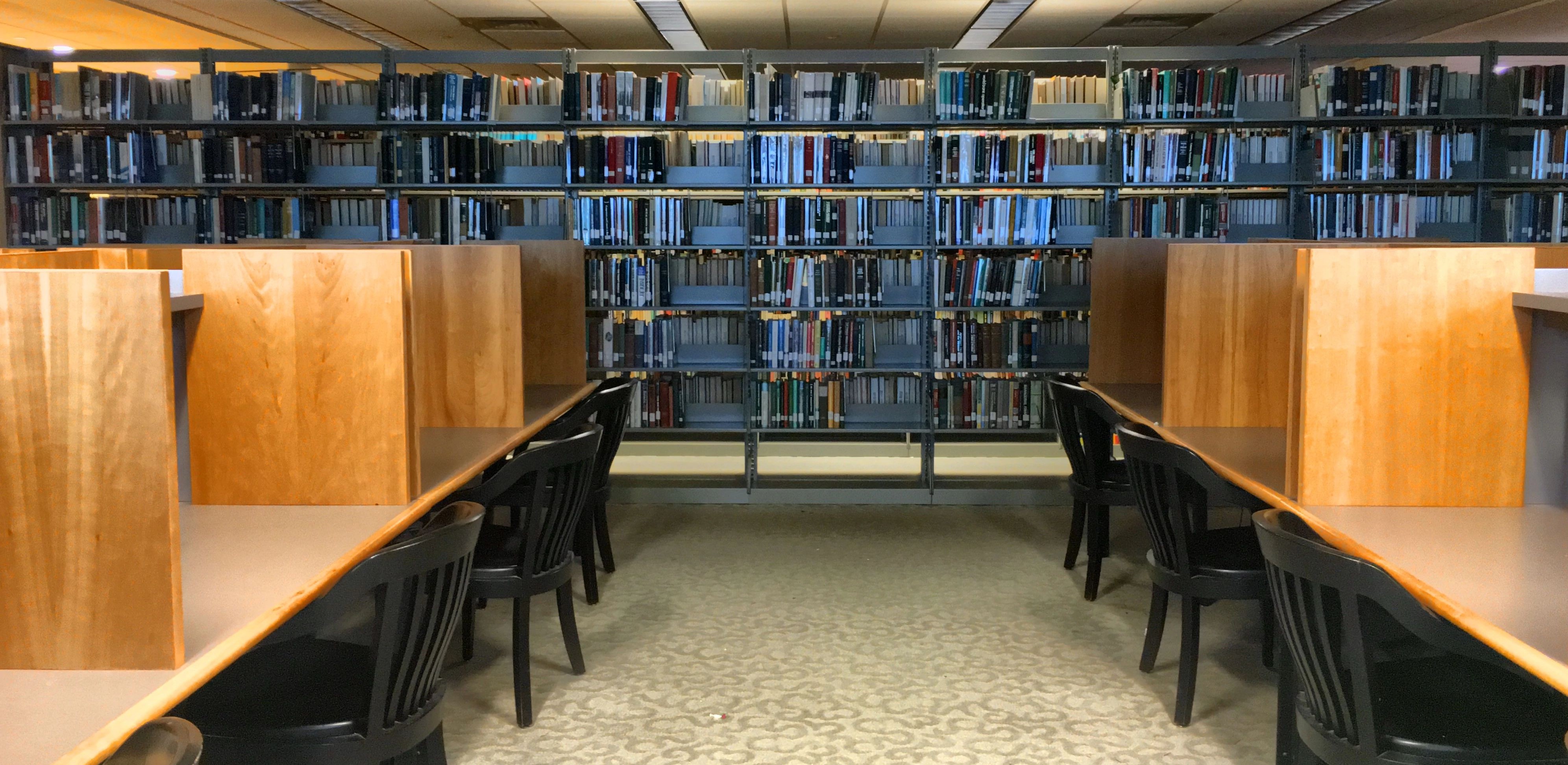 View of the library with study carrels left and right and books in the back 