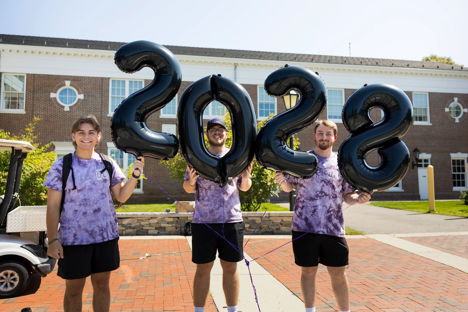 Orientation leaders in purple shirts holding balloons together that make 2028